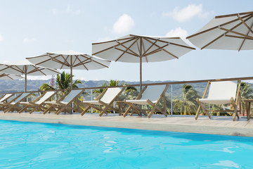 White deck chairs, umbrellas, mountains, side