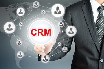 Businessman pointing on CRM (Customer Relationship Management) sign on virtual screen with people icons linked as network
