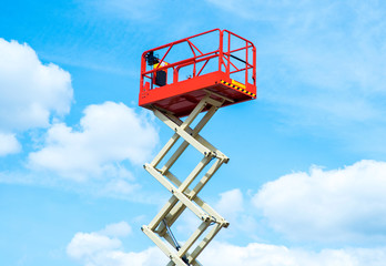 Hydraulic lift platform with bucket of yellow construction vehicle, heavy industry, blue sky and white clouds on background