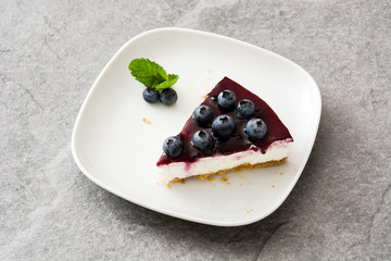 Piece of blueberry cheesecake on gray stone
