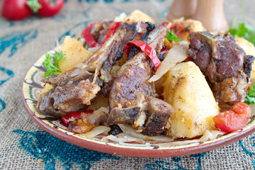 Traditional stew with lamb chops and vegetables: onion, cabbage, potato, tomato, paprika in a bowl on a cloth background. Healthy eating concept