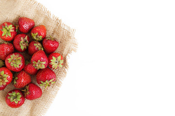 A pile of fresh juicy strawberries lies on an old sackcloth, iso