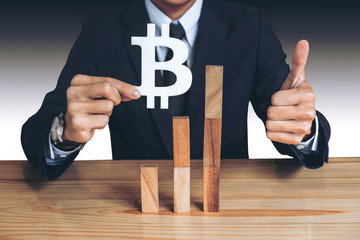 Financial growth concept, Businessman holding showing bitcoin symbol, concede Rise of price and the continued growth of the business. wooden block of the growth of income in bitcoins