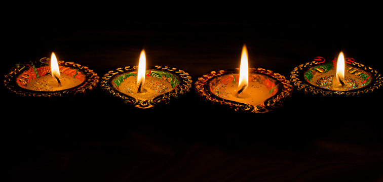 Four burning colorful candles indian style for Diwali celebration on black background. Vertical