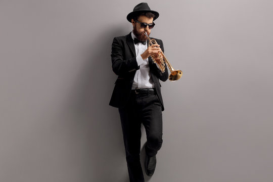 Trumpet player leaning against a wall