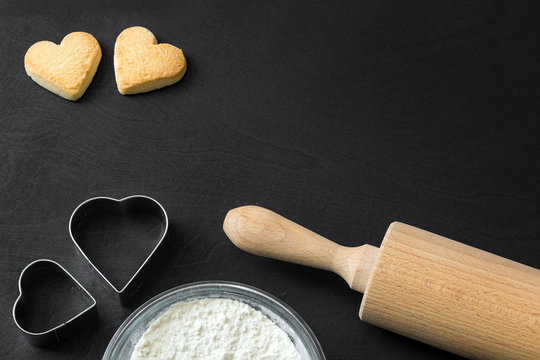 Geb&auml;ck Kekse mit Schokolade in Herzform liegen nach dem Backen mit Nudelholz dekorativ mit Backformen