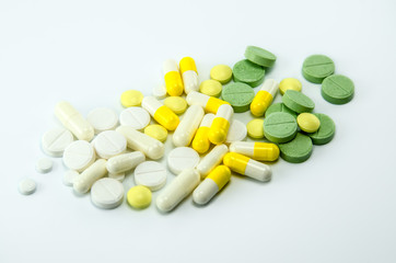 White, yellow and green pills on a white background.