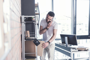 Trendy adult manager is laboring while talking on mobile phone