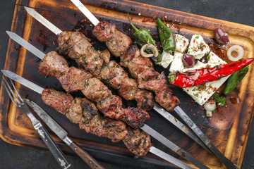 Traditional Greek Souvlaki with Feta and Vegetable as top view on an old burnt cutting board