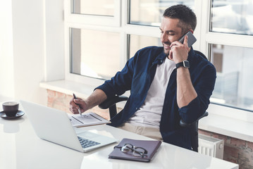 Stylish adult manager is having pleasant communication on smartphone