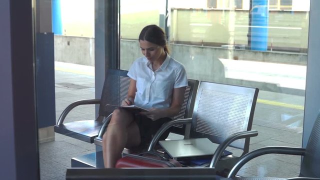 Young businesswoman working with documents sitting in the railway station
