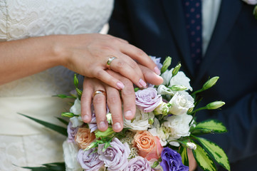 Obraz na płótnie Canvas Hands of the bride and groom on a bridal bouquet