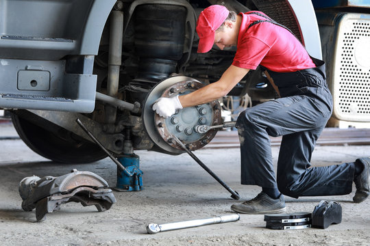 A mechanic repairs a truck. Replace brake disc and pads