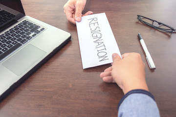 Image of businessman hand sending a resignation letter to executive boss with glasses, pen and laptop on  a wooden table, Change of job, unemployment, resign concept