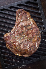 Barbecue dry aged Rib of Beef with salt and pepper as top view on a grillage