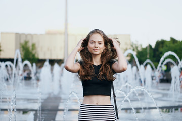 Young beautiful woman is walking along the street in the city in summer