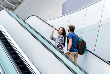 Cheerful couple is moving staircase leading up to departure area