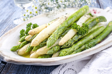 Boiled green and white Asparagus as top view on a plate