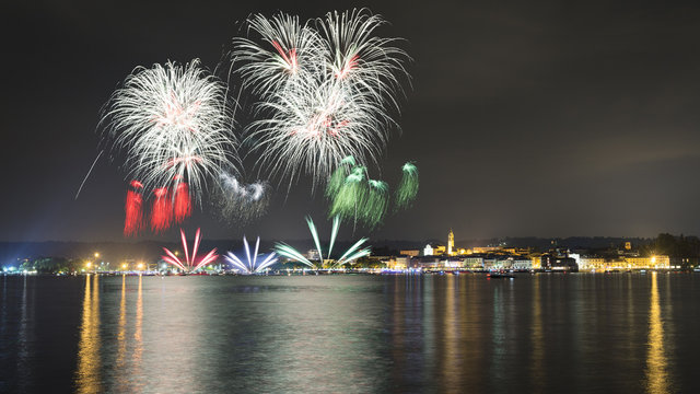 Fireworks on the lake in a summer night with city in the background