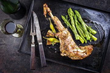 Barbecue Leg of Lamb with green Asparagus as top view on an old metal sheet