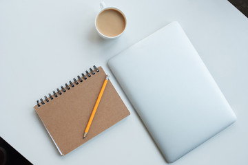 flat lay with laptop computer, notepad with pencil and cup of coffee isolated on white