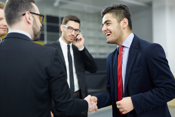 Happy businessman greeting his colleague by handshake