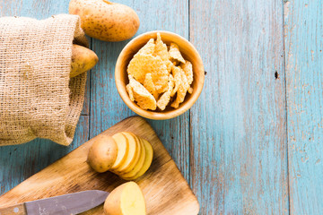 Pile of potatoes lying on wooden boards with a potato bag in the background