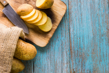Pile of potatoes lying on wooden boards with a potato bag in the background