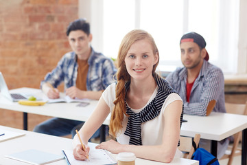 Diligent student sitting by desk at lecture