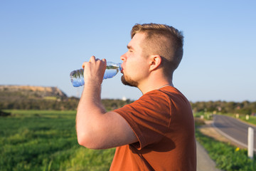 close up of a man drinking water from a bottle outside