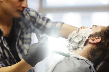 Young man visiting barbershop to shave beard