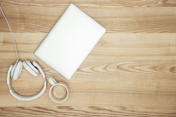 top view of laptop, headphones and coffee cup on wooden tabletop