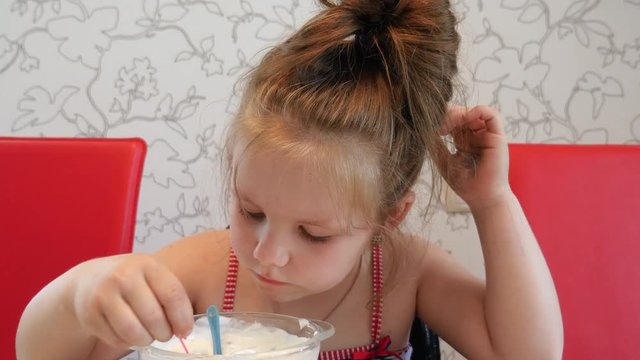 Little girl eats yogurt with berries. Lack of appetite.