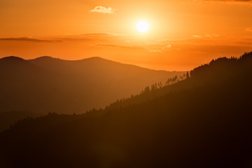 Silhouettes of mountain range in soft yellow morning light, nature landscape