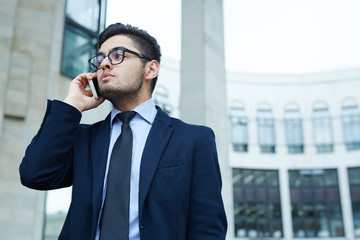 Serious agent speaking to client on smartphone