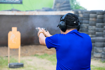Man Firing Pistol at Target in Shooting Range