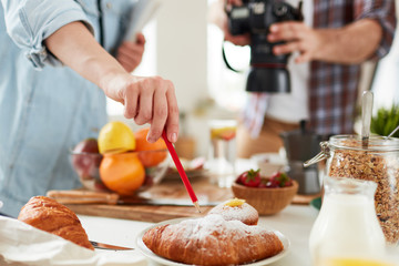 Food-stylist pointing at fresh croissant during working process