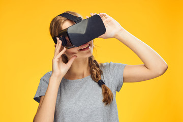 Young beautiful woman on a yellow background with virtual reality glasses