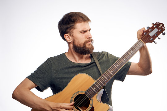 A man with a beard on a white isolated background holds a guitar, music, musical instruments, play, strings