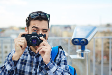 Obraz premium Portrait of handsome young man taking picture with vintage photo camera