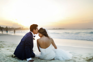 Fototapeta na wymiar Groom kisses bride's forehead sitting on the beach