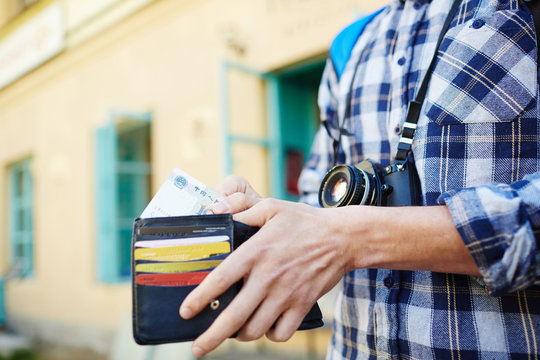 Closeup image of young tourist putting money in wallet