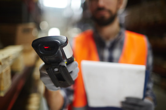 Closeup of bar code scanner in hand of unrecognizable warehouse worker doing inventory of stock
