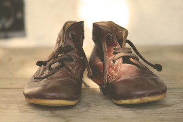 Old leather shoes on wooden flor; close up, selective focus.