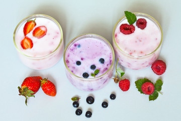 Homemade berry yogurt with strawberries, blueberries and raspberries in glass on a light table