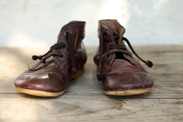 Old leather shoes on wooden flor; close up, selective focus.