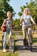 Obraz premium Positive girl and her gradnmother riding bicycles
