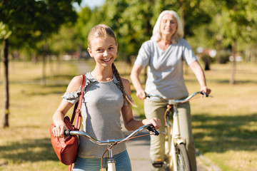 Fototapeta na wymiar Pretty smiling girl riding a bicycle with her grandmother