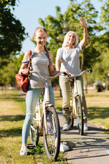 Obraz premium Joyful teenage girl riding a bicycle with her grandma
