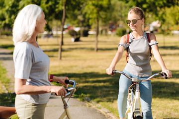 Naklejka premium Positive teenager girl enjoying riding bicycle in the park